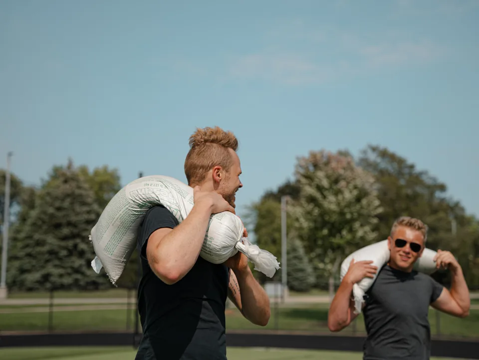 Two athletes carrying sandbags